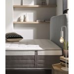 Vista elegante de un colchón premium sobre una base tapizada en un dormitorio moderno. El colchón luce capas acolchadas y tejidos suaves, transmitiendo confort, lujo y calidad superior.