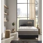 Vista elegante de un colchón premium sobre una base tapizada en un dormitorio moderno. El colchón luce capas acolchadas y tejidos suaves, transmitiendo confort, lujo y calidad superior.