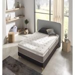 Vista elegante de un colchón premium sobre una base tapizada en un dormitorio moderno. El colchón luce capas acolchadas y tejidos suaves, transmitiendo confort, lujo y calidad superior.