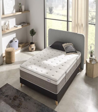 Vista elegante de un colchón premium sobre una base tapizada en un dormitorio moderno. El colchón luce capas acolchadas y tejidos suaves, transmitiendo confort, lujo y calidad superior.